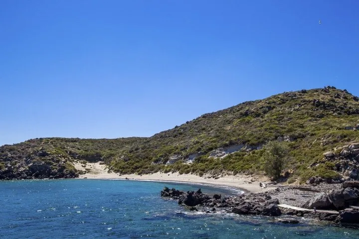 A secluded beach cove with clear blue water and rocky shores
